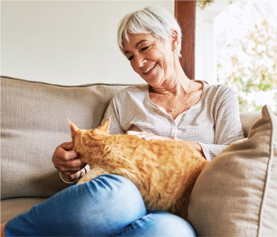 senior woman on the couch petting her cat