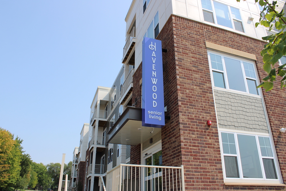 Main entrance of a modern, multi-story senior living building with a blue Havenwood sign