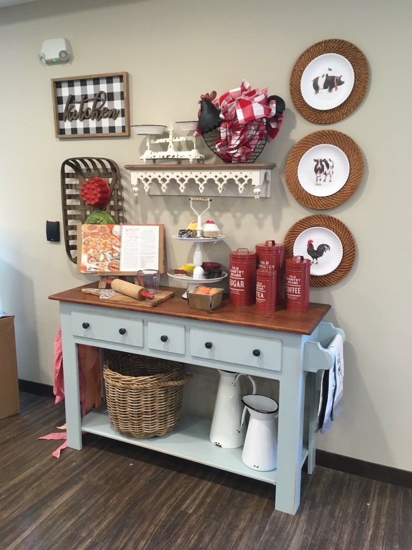 Rustic kitchen sideboard with decor, red canisters, recipe book, and farmhouse themed plates