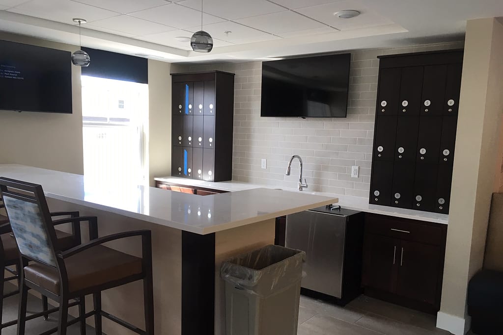 Cozy bar with barstools, dark wood cabinets, and a mounted TVs.