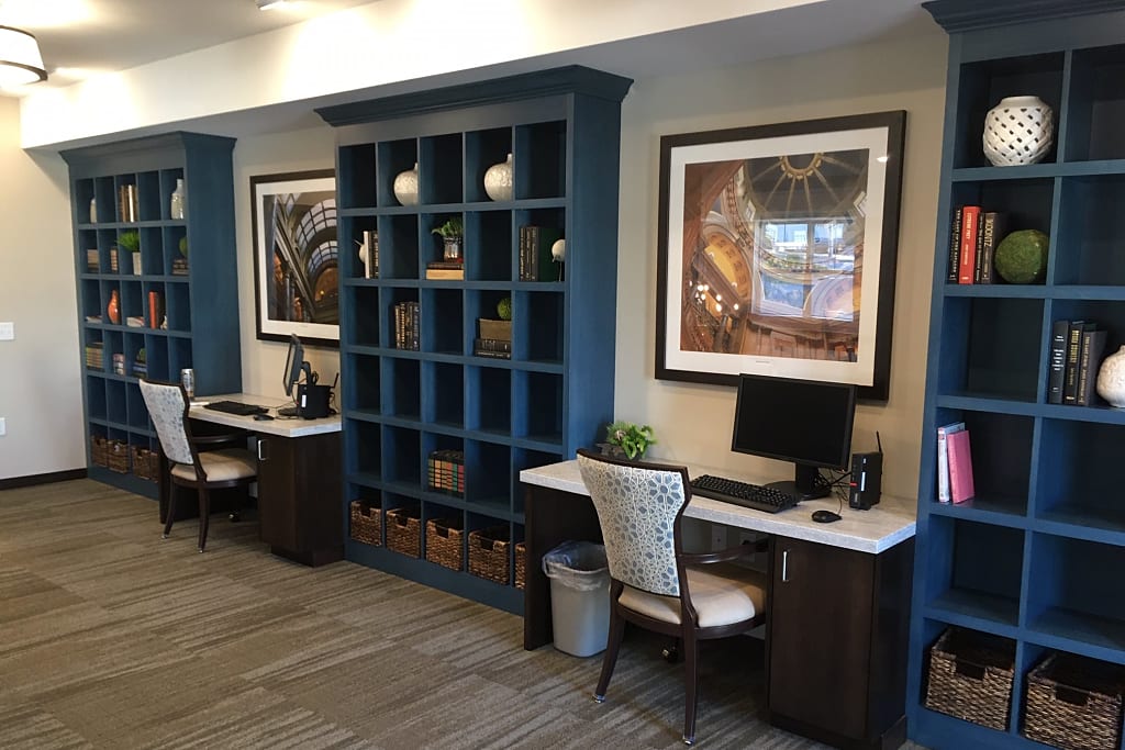 Business center with desks, chairs, computers, and large bookcases.