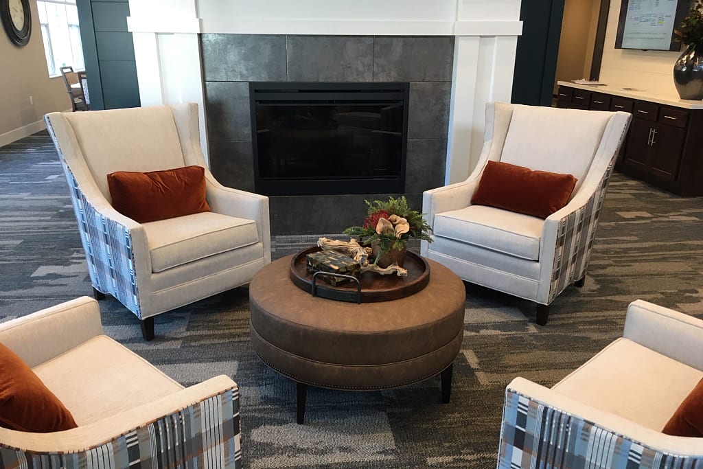 Seating area with four armchairs around a coffee table and a fireplace.