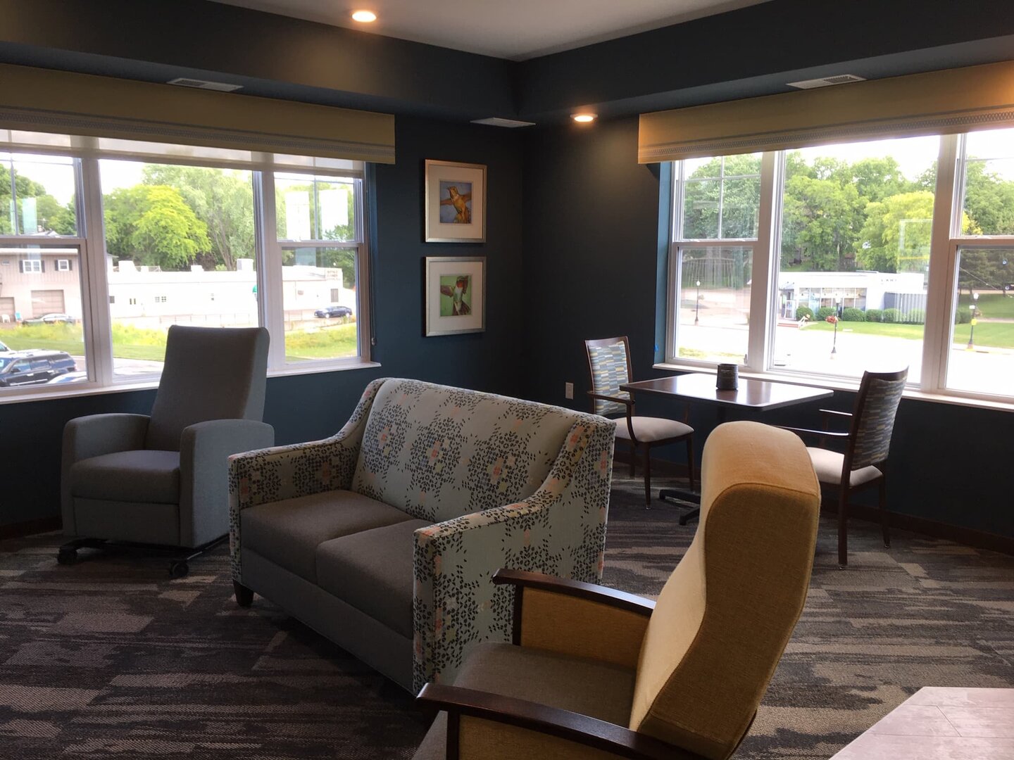 Cozy seating area with armchairs, sofa, and table in a senior living unit.