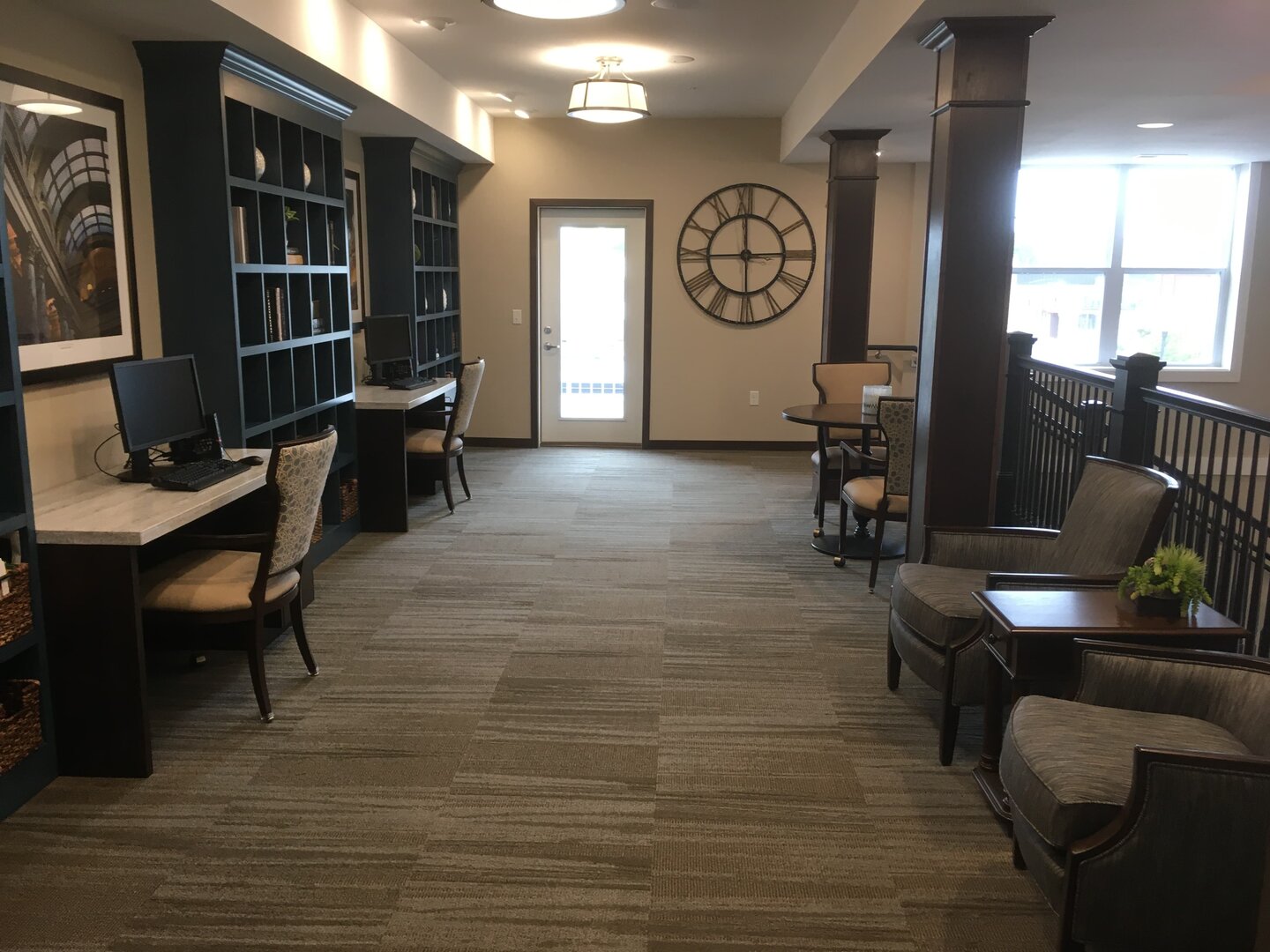 Cozy seating area with computers and large clock in communal space.