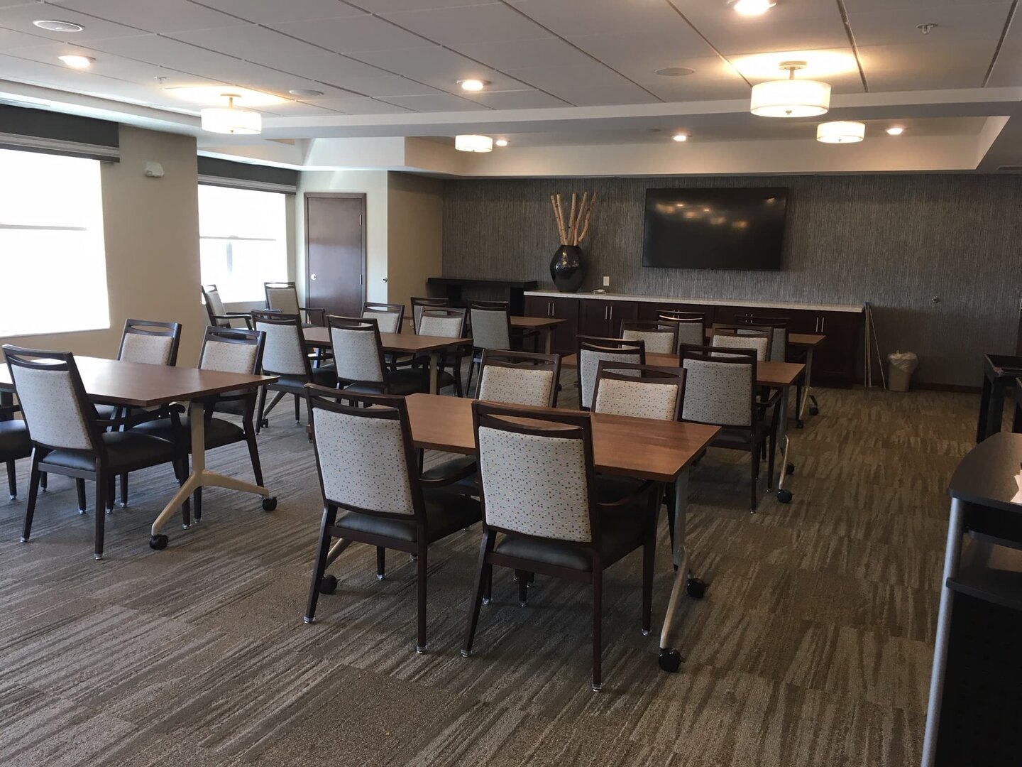 Community room with tables and chairs in a senior living building.