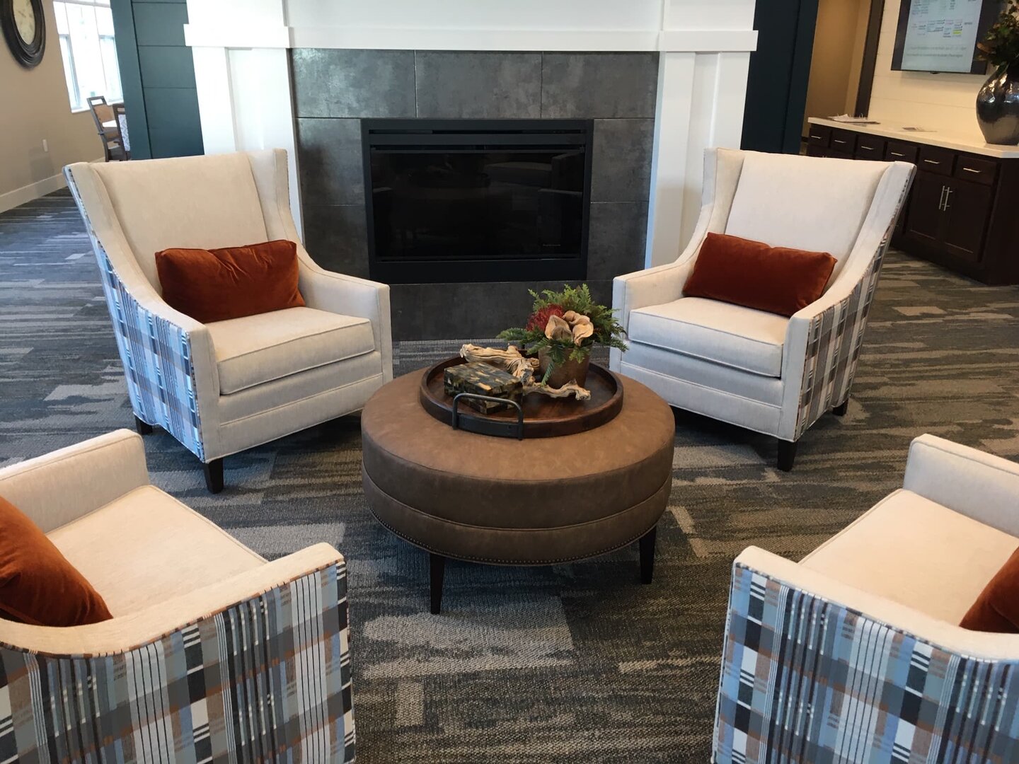 Cozy seating area with four armchairs around a fireplace in a community lounge.