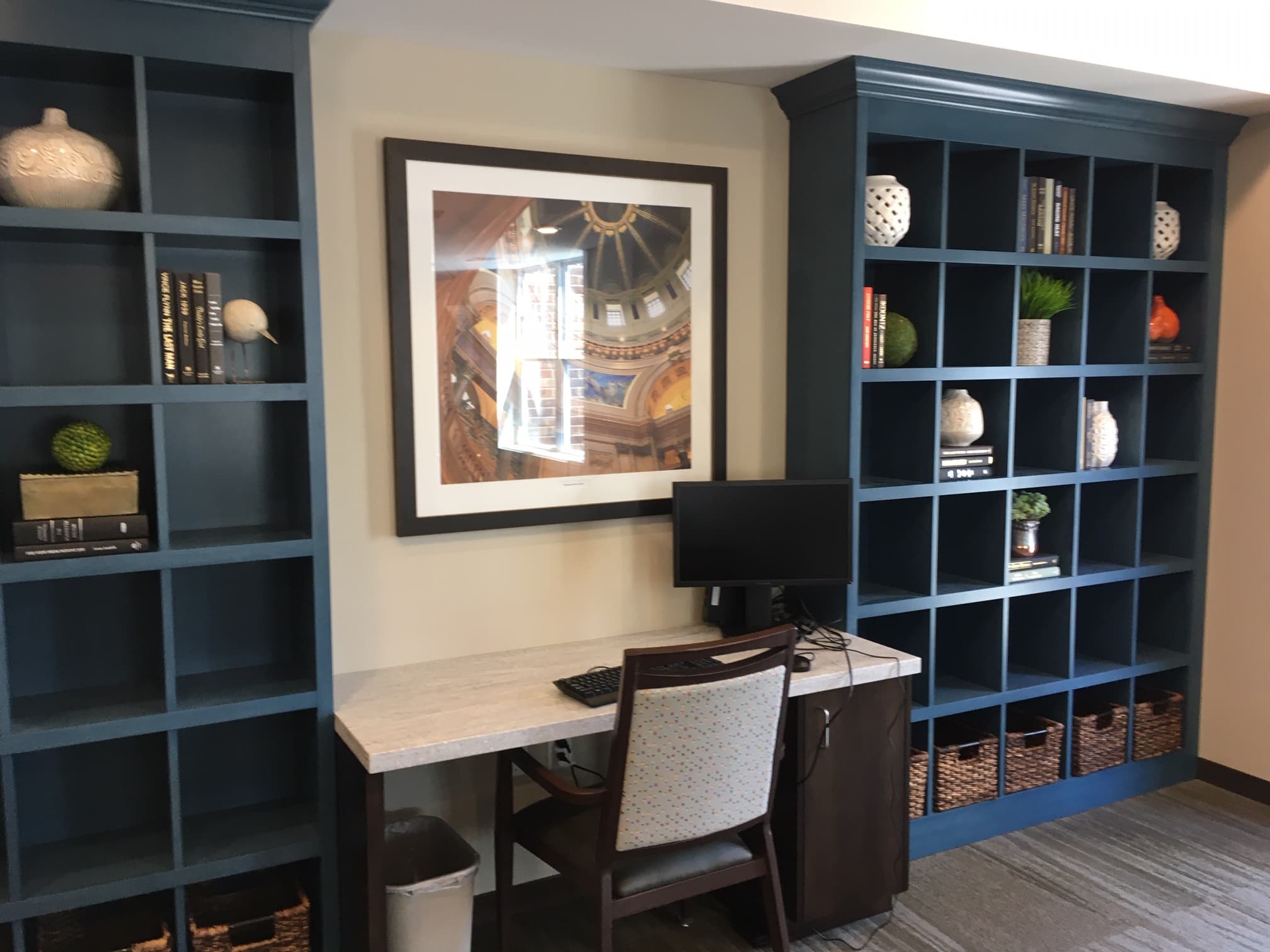 Study nook with desk, chair, and blue shelves in a community living area