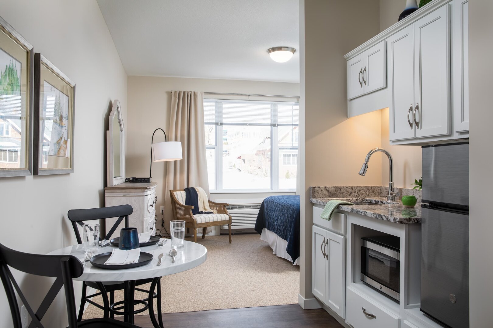 Modern living unit with cozy bedroom, kitchenette, and dining area with natural light.