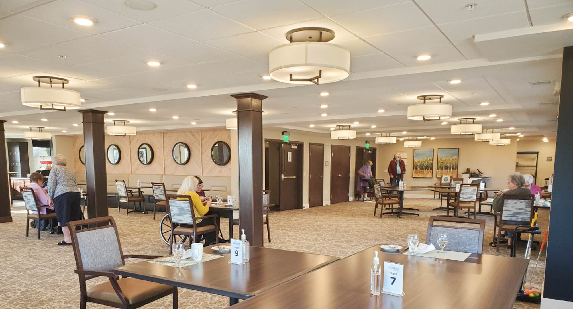Spacious dining room with residents and staff in a senior living community.