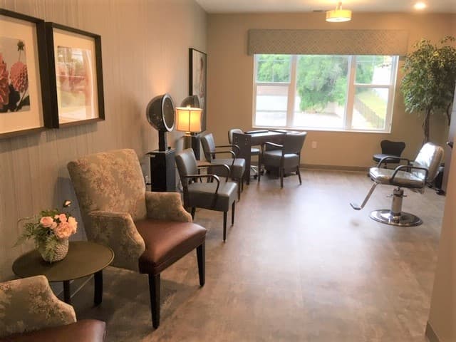 Cozy salon area in senior community with chairs, decor, and large window view.